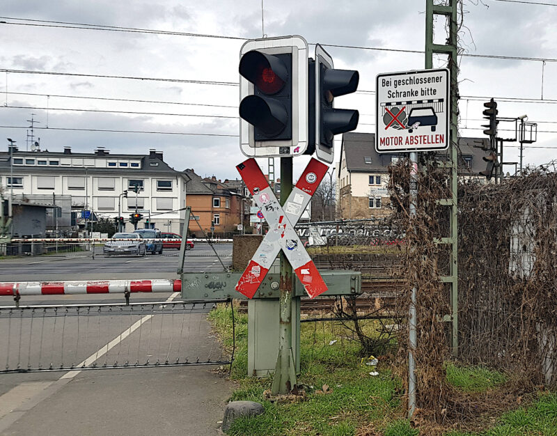 Bahnübergang Hochheimer Straße – „Bitte Motor abstellen bei geschlossener Schranke“  Das Schild am Bahnübergang Kastel könnte als Vorbild dienen.